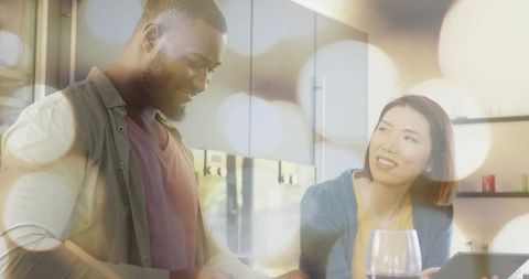 Couple cooking together in modern cozy kitchen with warm bokeh lighting, tablet and wine