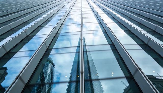 Reflecting glass facade drawing eye upward toward towering urban skyscrapers and skyline