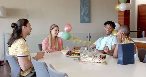 Friends Enjoy Social Gathering Around Dining Table with Snacks