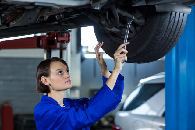 Female mechanic fixing a car wheel disc brake in repair garage