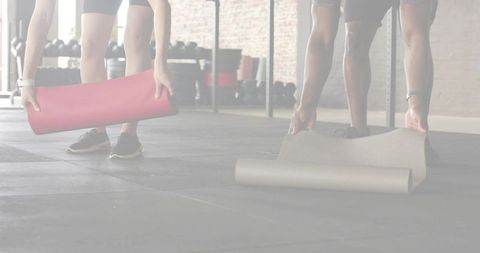 Unrolling red and gray exercise mats in industrial gym preparing for partner workout