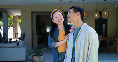 Young couple sharing gentle embrace on covered patio with cozy plants and warm lighting