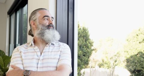 Senior Man Contemplating by Bright Window in Home Interior