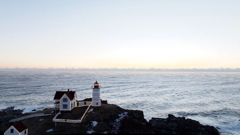 Seaside lighthouse overlooking ocean at sunrise