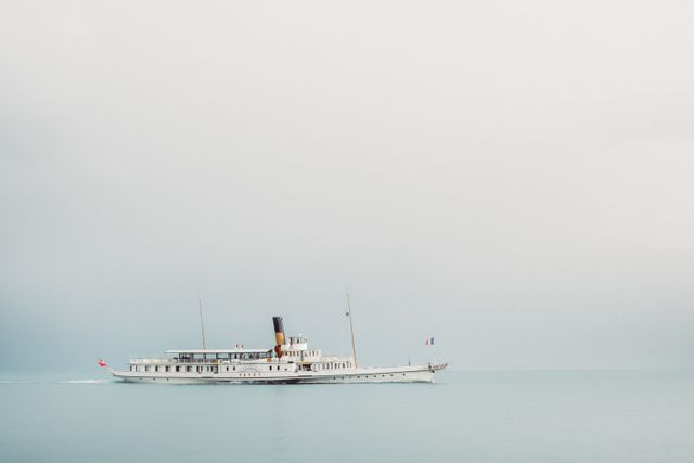 Ideal for travel blogs, maritime history features, and minimalist art collections. This image captures a vintage passenger steamboat sailing on a calm sea with a minimalist sky, conveying tranquility and nostalgia.