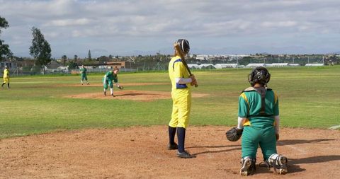 Dynamic female softball game action with players competing outdoors