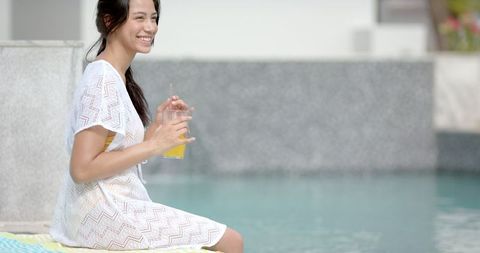 Carefree Teenage Girl Relaxing with Juice by Pool