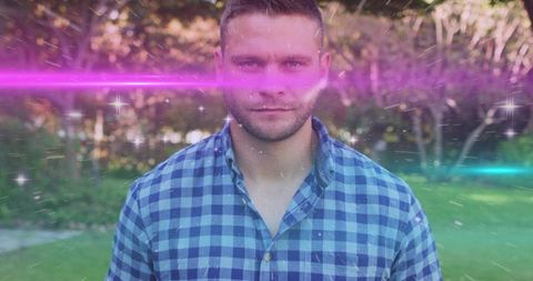 Standing man in checked shirt facing camera with magenta and teal light streaks and dreamy bokeh
