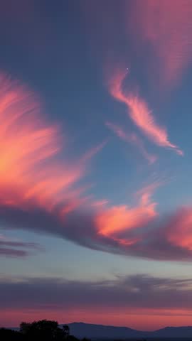 Vertical video showcasing pink clouds drifting over silhouetted ridge at dusk with planet