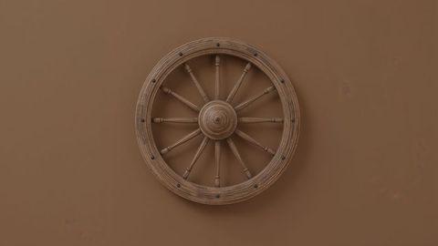 Wooden wagon wheel on brown wall for rustic decor