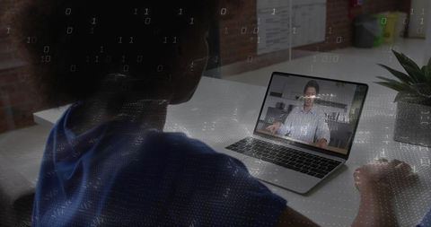 Woman joining remote video meeting on laptop with digital binary overlay in workspace