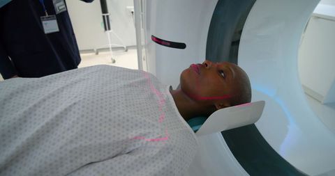 Patient receiving ct head scan with laser alignment and technician guidance in radiology suite