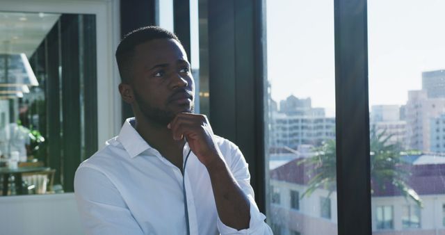 Thoughtful Young Man in Office with City View - Download Free Stock Images Pikwizard.com