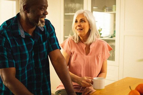 Senior couple smiling and talking over coffee in modern kitchen