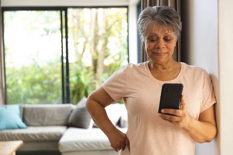 Senior woman checking smartphone in bright living room