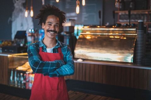 Confident barista smiling in trendy cafe with warm lighting