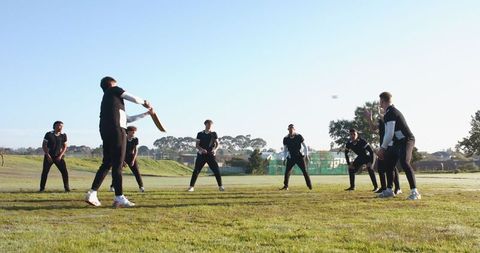 Diverse team practicing cricket outdoors enthusiastically