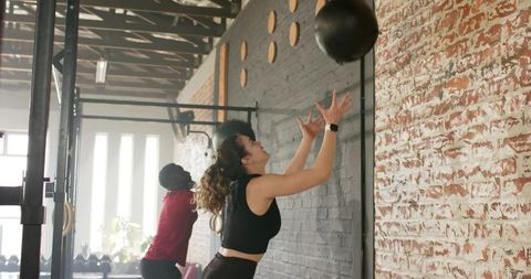 Athletes Performing Wall Ball Workout in Industrial Gym Environment