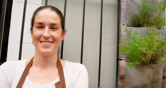 Smiling Woman with Apron Next to Vertical Garden - Download Free Stock Images Pikwizard.com