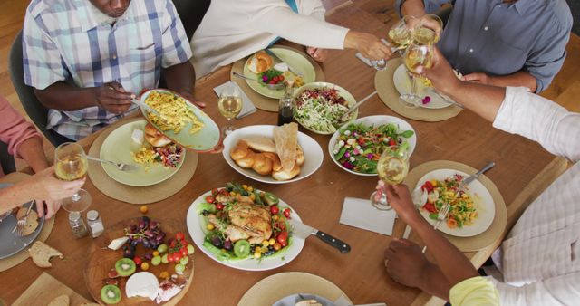 People gathered around dinner table enjoying a diverse selection of healthy salads, main dishes, and wine. The setting promotes socializing, gathering, and sharing among friends. Ideal for advertising social events, celebrations, and healthy living concepts.