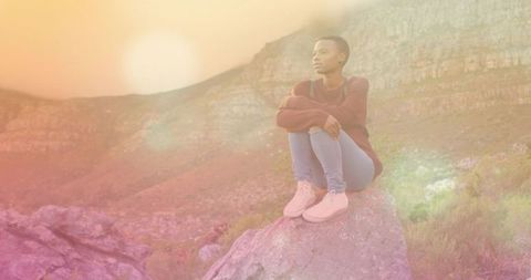 Woman in Sweater Reflecting on Boulder During Sunset in Mountainous Trail