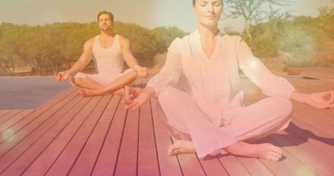 Couple meditating on wooden pool deck at sunrise practicing mindfulness and relaxation