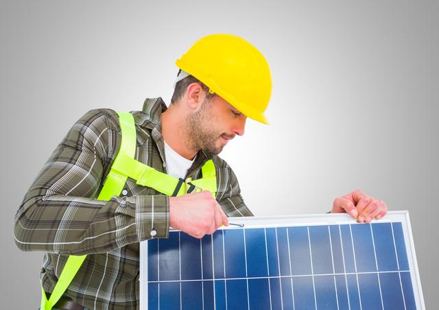 Worker fixing solar panel against grey background