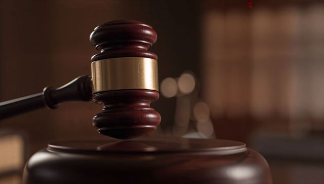 Dark polished judge gavel resting on sounding block brass-banded closeup courtroom justice