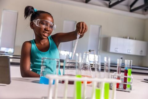 African american girl conducting colorful chemistry experiment in classroom laboratory