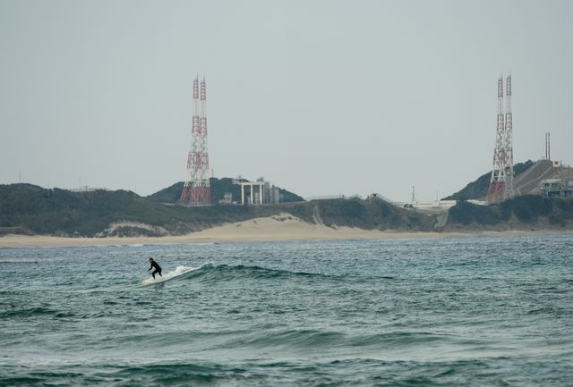 A surfer navigates the ocean waves in front of Tanegashima Space Center in Japan on February 23, 2014. The TNSC is known for space launches, such as the planned NASA-JAXA Global Precipitation Measurement Core Observatory launch on February 28, 2014. Ideal for articles on space exploration, recreational activities near space facilities, or beach sports.