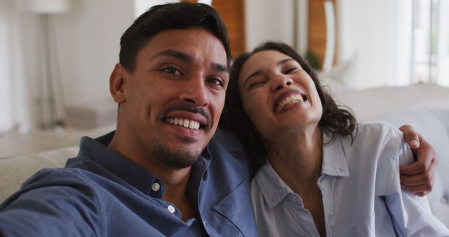 Romantic hispanic couple embracing sending kisses on sofa in living room. at home in isolation during quarantine lockdown