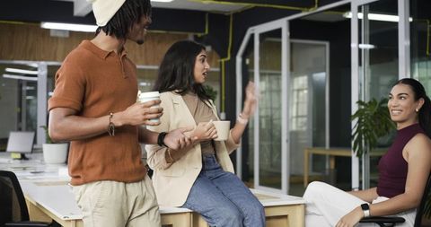 Diverse coworkers chatting and collaborating in modern office casual meeting around desk