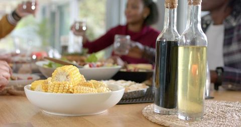 Diverse Friends Sharing Sunlit Meal Passing Bowl of Corn on Cob