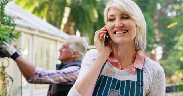 Smiling Woman on Phone in Backyard Garden with Man Working - Download Free Stock Images Pikwizard.com