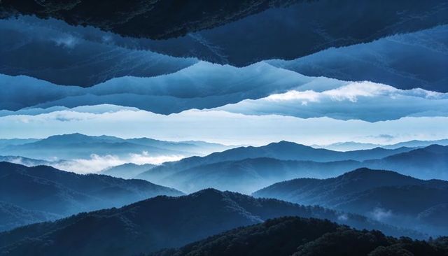 Dreamlike blue mountain layers receding into misty valleys with cloud bands, atmospheric