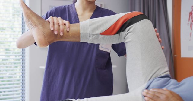 Physical therapist guiding patient through leg rehabilitation exercise in a clinical setting. Useful for promoting healthcare, medical care, physiotherapy institutions, rehabilitation centers and articles related to recovery and therapy practices.