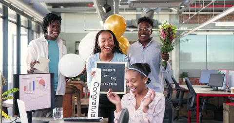 Diverse Team Celebrating Promotion with Balloons and Flowers in Office
