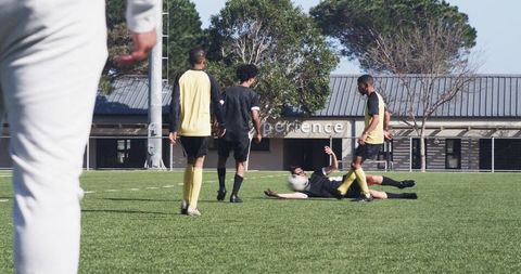 Soccer players supporting a fallen teammate on field