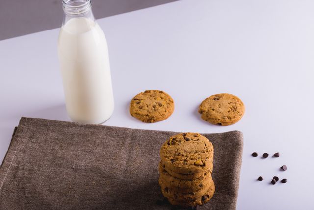 Milk bottle by cookies with chocolate chips and napkin on white background, copy space. unaltered, food, drink, studio shot and healthy eating.