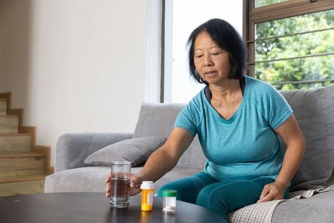 Senior Asian Woman Taking Medication at Home