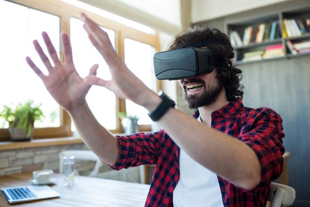Happy man using virtual reality headset in coffee shop