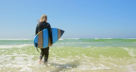Senior Female Surfer with Surfboard walking into Ocean Waves on Sunny Day - Download Free Stock Images Pikwizard.com