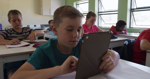 Focused boy using tablet in diverse school classroom, education technology - Download Free Stock Images Pikwizard.com