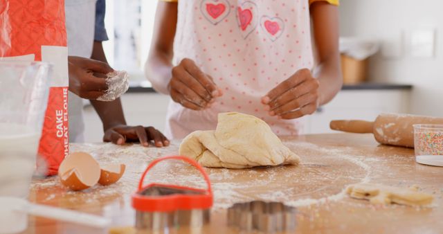 Children baking cookies together in the kitchen, learning new skills. Hands shaping dough with flour, ingredients, and baking tools like rolling pin and cookie cutters visible. Ideal for educational, lifestyle, or family-oriented projects, as well as blogs and websites focused on activities for kids.