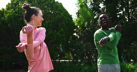Diverse Couple Exercising Amid Greenery and Laughing