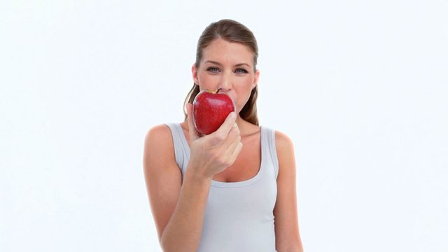 This video of a woman holding and preparing to eat a red apple can be used for promoting healthy eating habits, diet guides, nutritional content, and wellness blogs. It symbolizes freshness, health, and nutritious choices, making it ideal for materials focusing on fitness, dieting, and overall well-being.