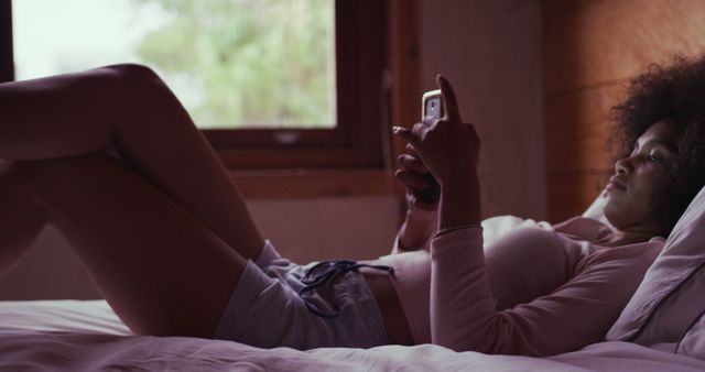 Woman relaxing on bed while using smartphone - Download Free Stock Images Pikwizard.com