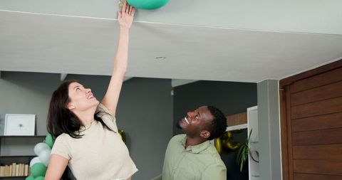 Couple removing party decorations after celebration in living room