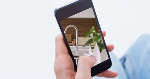 Person Viewing Modern Kitchen Design on Smartphone Screen