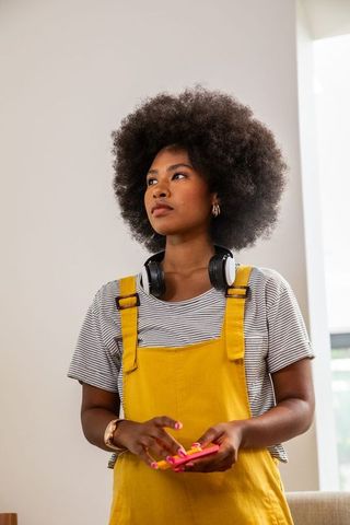 Afro hairstyle woman with headphones holding smartphone